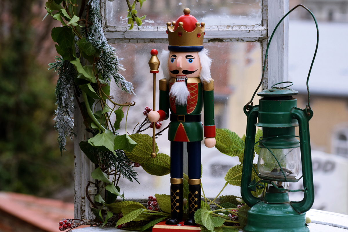 A holiday display that features a vintage nutcracker and antique kerosene lantern