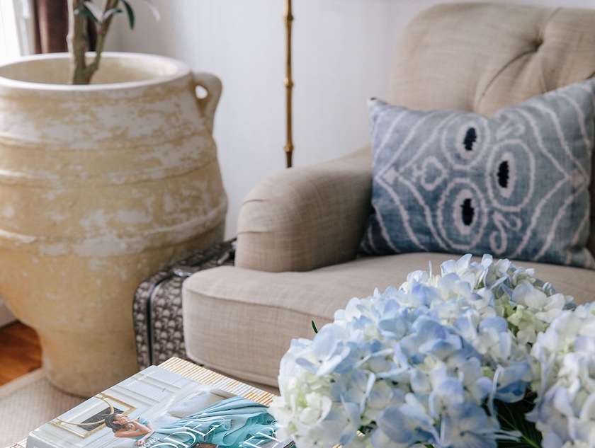 An oversized pot is used as a giant planter with a faux tree in the corner of a well-styled living room